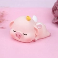 Cute pink pig cake topper with golden ingot and wings in a sleeping pose - Sleeping Squinting