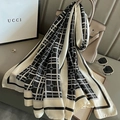 Black and white plaid silk scarf draped over a beige handbag in a luxury indoor setting - Black