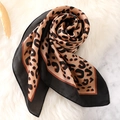 Detail of leopard print silk scarf showing soft texture and glossy finish on plush surface - 70x70cm / Yellow Black Border Leopard