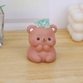 Figurine d'ours brun-rose mignonne avec cristaux verts sur un bureau en bois clair - Ours