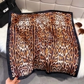 Macro detail of silk-like leopard print scarf with black border on faux fur surface - Black
