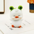 Cute duck car ornament wearing a green frog hat for dashboard and office desk decor - Squinting White Shaking Head Duck (0033)