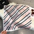 Close-up of geometric striped silk scarf with pink and blue patterns and rolled edges - Pink