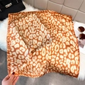 Detailed view of the leopard print silk scarf with fine edge stitching and smooth texture - Warm Orange Brown