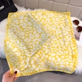 Detail of yellow and white leopard print silk scarf texture and fine stitched edges - Yellow