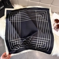 Dettaglio foulard in seta con motivo geometrico bianco e nero su tappeto di ecopelliccia - 65*65cm / Nero