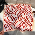 Detailed view of red and white wave print silk scarf styled on white faux fur with a handbag - Red and White Wave Grid / Red