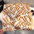 Close-up of wavy orange and white checkerboard silk scarf on a plush background - Orange and White Wave Chessboard / Orange