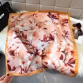 Elegante zijden sjaal met camelia-print en satijnen afwerking op witte imitatiebont achtergrond - Oranjeroze