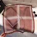 Dettaglio di un foulard quadrato marrone a pois su pelliccia sintetica bianca con accessori - Borgogna