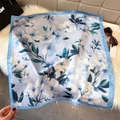 Detailweergave van zijden sjaal met camelia-bloemenprint op een pluchen achtergrond - Hemelsblauw