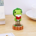 Cute green frog reading a red book spring ornament on wood stake base for office desk - Reading Frog Spring Ornament (0389B)
