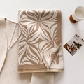 Detail van wintersjaal met abstract bruin bloemenpatroon en franjes aan de rand - camel