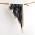 Elegante sciarpa in seta a pois drappeggiata su un ramo naturale su sfondo grigio chiaro - Nero