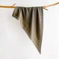 Close-up of silk-textured triangle scarf with letter prints hanging on a wooden branch - Grey Green