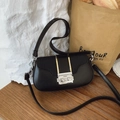 Sac bandoulière noir rétro avec rabat tressé et fermoir argenté sur un bureau en bois - Noir