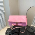 Pink lychee texture shoulder bag with gold chain strap held in a cozy indoor setting - Pink