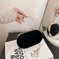 Elegant black velvet clutch bag with golden circular handle and chic bow buckle - Black