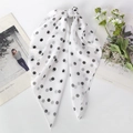 Detail of white chiffon scarf with black polka dots tied in a bow next to a daisy flower - White