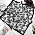 Artistic detail of a folded silk square scarf with shell patterns and stylish sunglasses - Big Shell Black