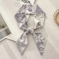 Detailed view of a purple French toile pattern silk scarf tied in a bow on a white magazine - Letter T (Purple Illustration Toile)