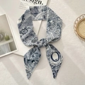 Detail of blue floral print silk scarf tied in a bow on textured beige background - Letter O (Blue and White Line Drawing Pattern)