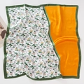 Close-up of floral silk square scarf with orange patchwork and soft fabric folds - Floral