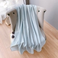 Gros plan d'une écharpe en coton bleu clair drapée sur une chaise sous lumière douce - Version Étendue / Zircon Bleu Clair