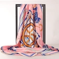 Elegant pink silk scarf with nautical ship wheel print draped on a minimalist black rack - Pink Nautical Rudder