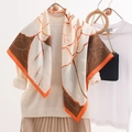 Elegant 90x90cm camellia print silk scarf with orange border draped over beige sweater - Large Square Scarf / Light Brown