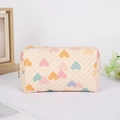 Detail of cream pencil case with colorful heart prints and 3D chevron quilted texture - Yellow