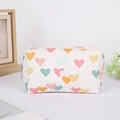 Macro shot of white quilted pencil case with colorful heart prints and metal zipper detail - White