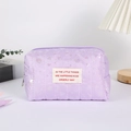 Detalle de estuche morado acolchado con patrones de corazones y etiqueta tejida blanca - Morado