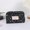 Detail view of black quilted pencil case with colorful heart prints and fabric label - Black