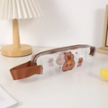 Detailansicht des klaren Capybara Federmäppchens mit braunem Reißverschluss und Tragegriff - Capybara-Stil (Orange haltend)