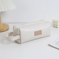 Detail van verticaal gewatteerde textuur en lederen patch op crème grote capaciteit etui - Broken Wit