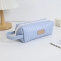 Detail van een lichtblauw gewatteerd etui met stoffen handvat en leren label - Hemelsblauw