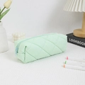 Close-up of light green quilted pencil case with geometric diamond patterns and zipper - Green