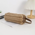 Detailoverzicht van een bruin gestreept pluche etui met lederen handvat en ritssluiting - koffiekleur