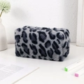 Detailansicht der flauschigen Leopard-Kosmetiktasche auf einem minimalistischen Schreibtisch - Grau