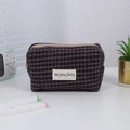 Detail of vintage purple plaid makeup bag featuring a fabric label and beige zipper closure - Grid Purple