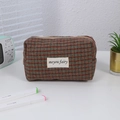 Close-up of checkered makeup bag in wool texture with woven label and metal zipper - Camel Grid