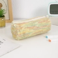 Detail of striped plush pencil case with zipper closure on a clean desk workspace - Yellow