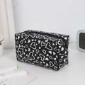 Close-up of black heart print cosmetic bag with metallic silver patterns and zipper - Black