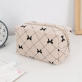 Detail of cream corduroy makeup bag featuring black bow patterns and silver zipper - Beige Bow