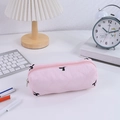 Roze gewatteerde etui met strikborduursel op een bureau met schrijfwaren en lamp - Roze