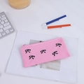 Dettaglio dell'astuccio in tela rosa con fiocchi neri su una scrivania da ufficio - Rosa