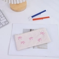 Dettaglio del ricamo a fiocco rosa su astuccio in tela crema e borsa per cosmetici - Beige