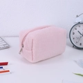 Close-up of a soft pink plush pencil case with zipper on a minimalist white desk - Pink