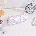 Detailed view of white quilted pencil case with bow prints and pink zipper on a desk - White